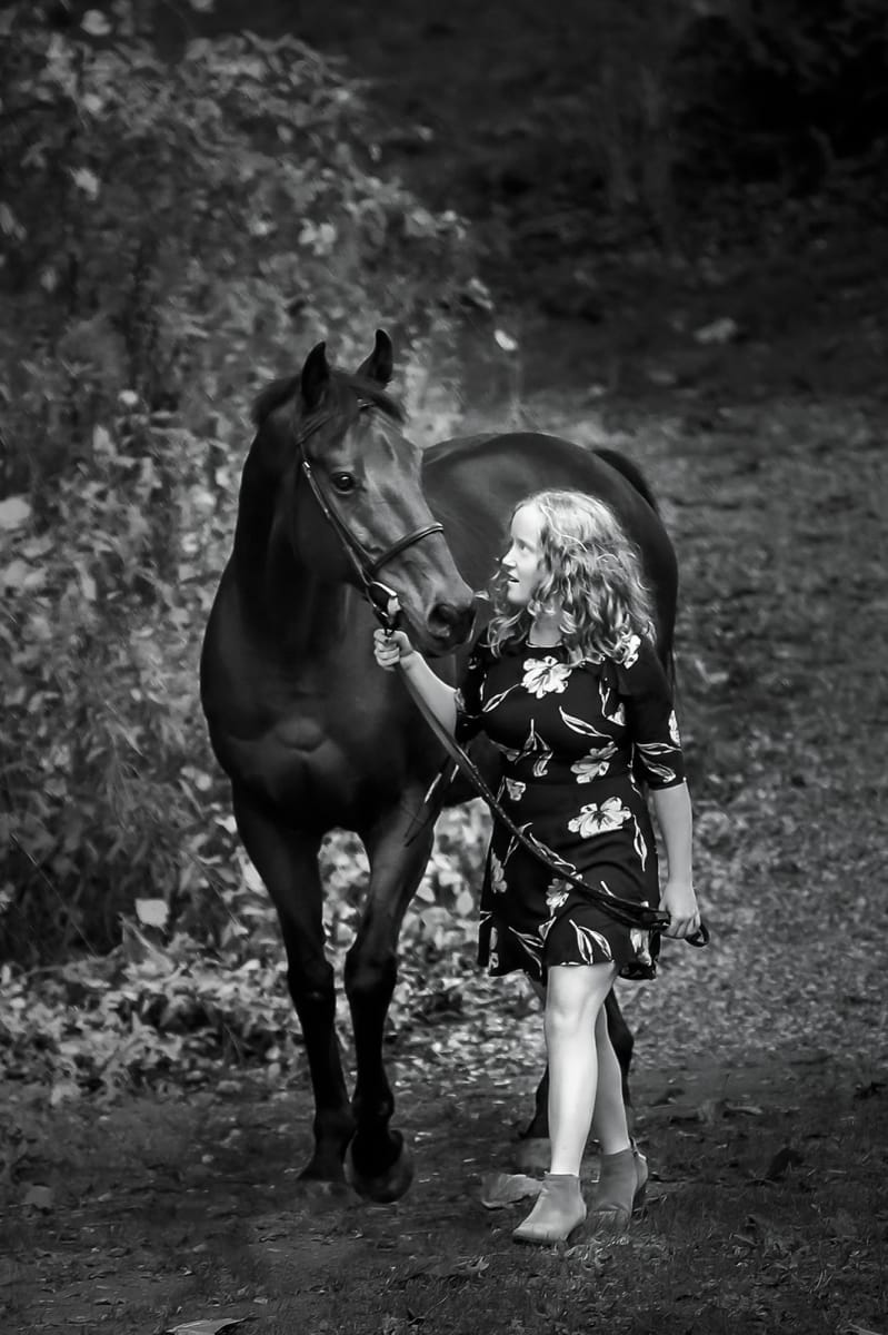 Black and white photo captured by a Detroit equine photographer, showcasing the bond between a horse and its owner holding the reins.