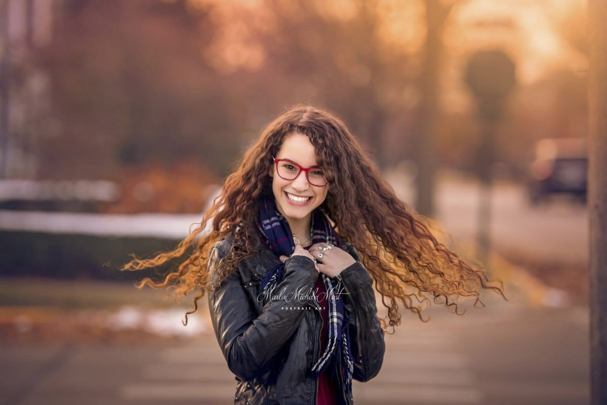 Autumn senior photo in Michigan city with long, curly hair and glasses