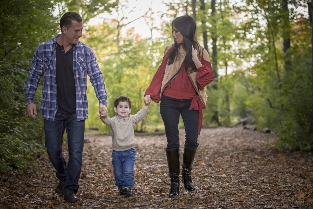 Detroit couple walk hand in hand with their child during an autumn family photoshoot.