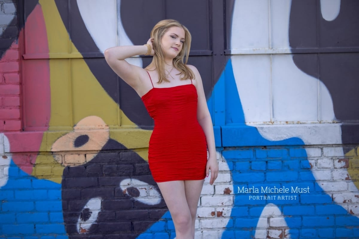 A fashion-forward photoshoot of a high school senior posing in front of a graffitied wall in Detroit