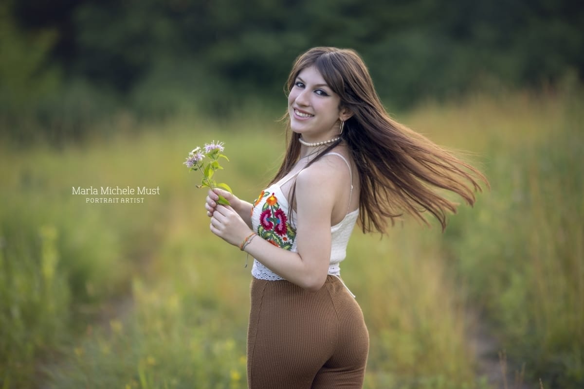 whimsical senior picture holding flower with hair flowing