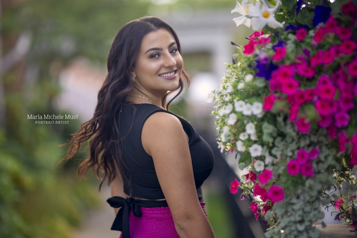 A high school senior happily stares over her shoulder among beautiful flowers during a Detroit senior photoshoot