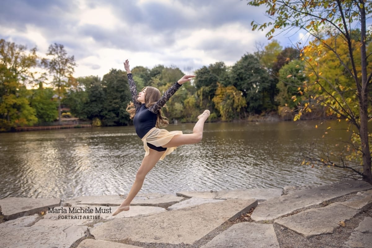 A skilled dancer propels into a graceful jete lakeside on a Michigan dock, captured in a striking portrait by a Detroit photographer.