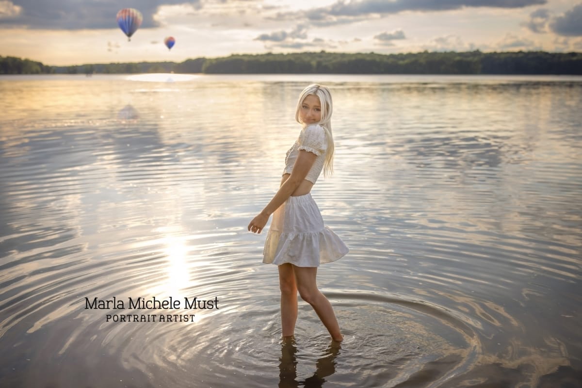 Classy senior photo of a girl in a white dress standing in the shallow waters of Michigan's Great Lakes.