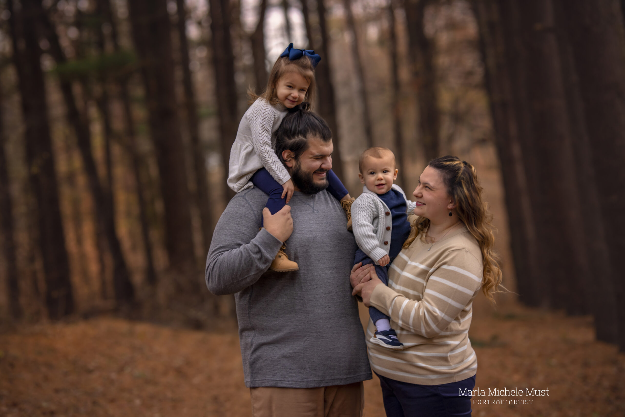 Comfy fall family photoshoot with a couple and their two children being held in their arms and on shoulders