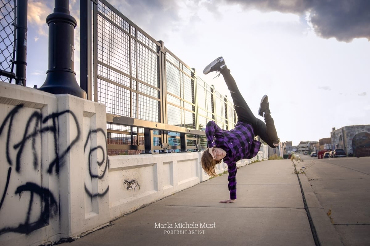 Dancer strikes a dynamic hip hop pose, exuding flair and style in a Michigan metro area cityscape.