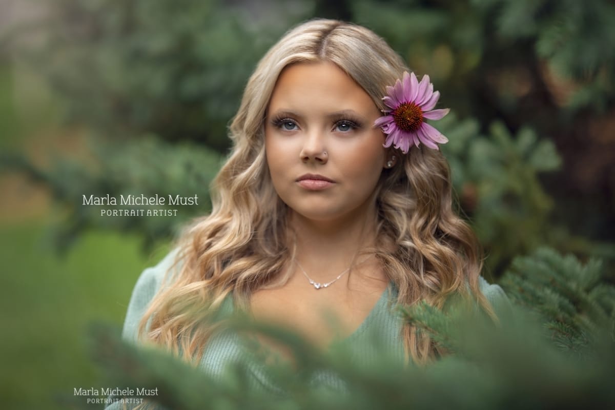 classic senior portrait of a blonde of a blonde girl with flower in hair - she is standing in a Detroit garden taken by a skilled Michigan high school portrait photographer.