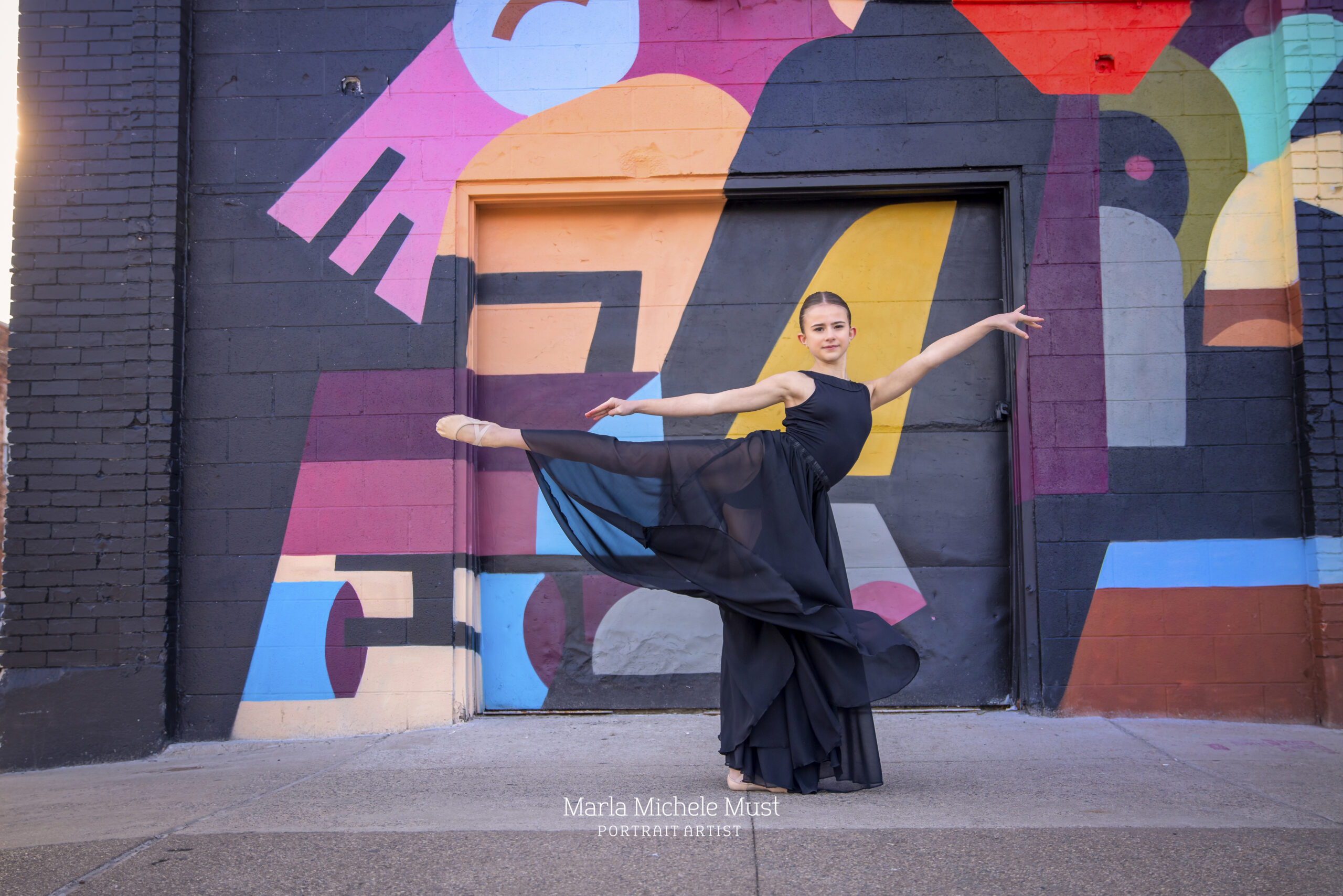 Dancer's leg and arm extensions through her light blue dress shine in this stunning dance portrait, captured by a talented Detroit photographer in front of a brightly colored abstract mural.