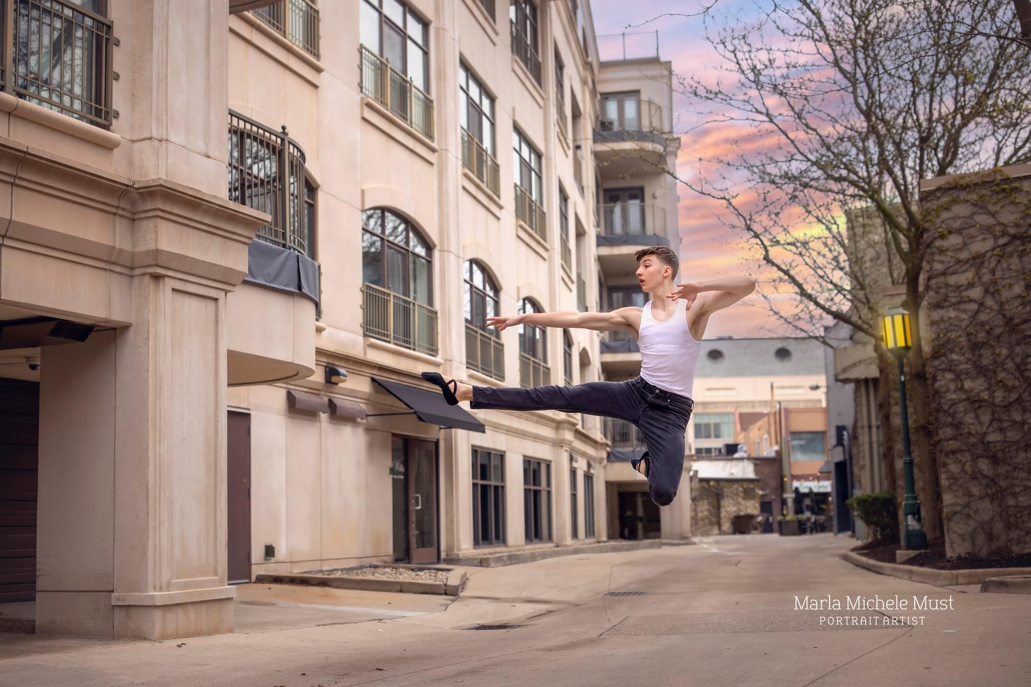 Man jumps in the air with one leg outstretched in downtown Detroit during a dance photoshoot, taken by a Michigan dance photographer.