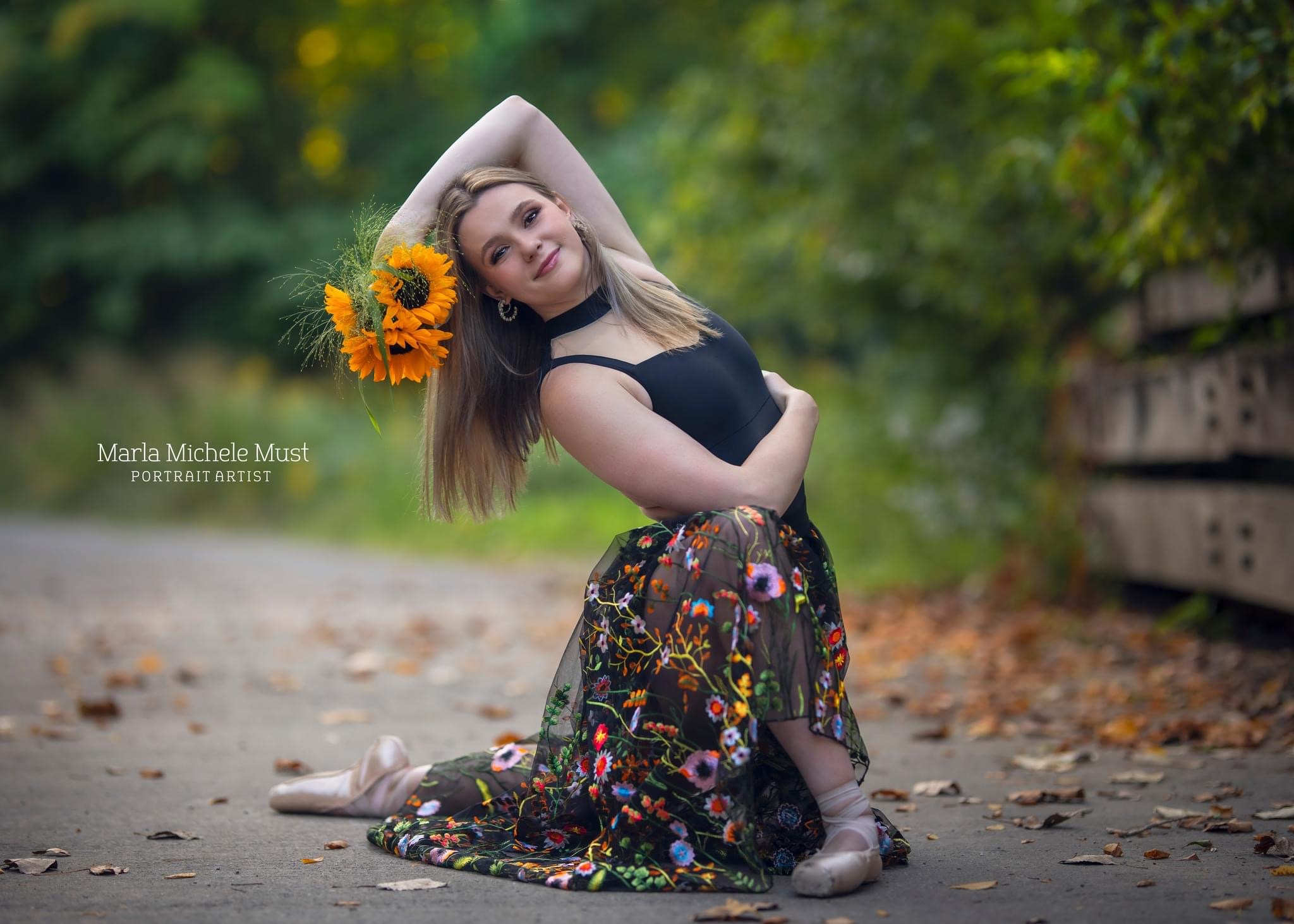A young woman poses for her senior photoshoot in Detroit while dancing with sunflowers