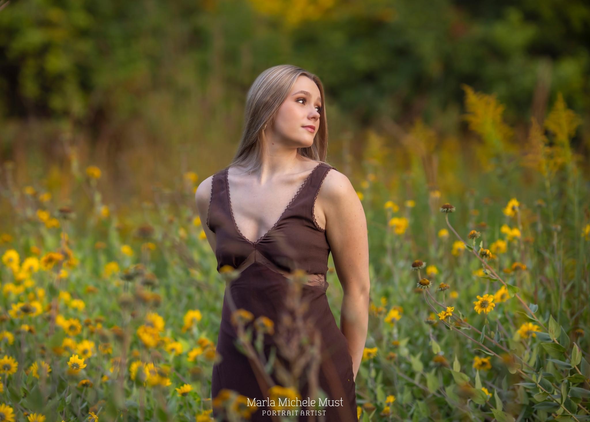 A young woman poses for her senior portrait in a field of wildflowers somewhere near Detroit