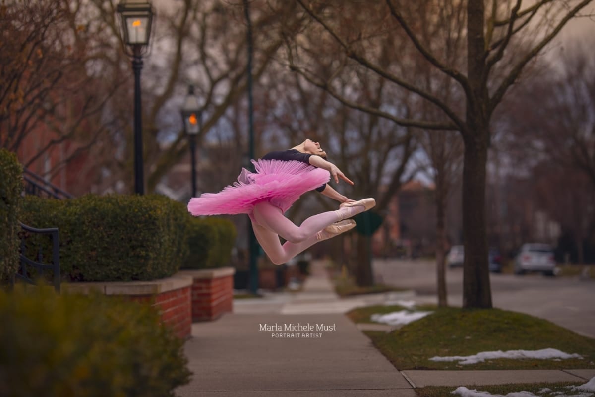 Dancer in a pink tutu soars through the air in a graceful leap, beautifully captured by a Detroit portrait photographer.