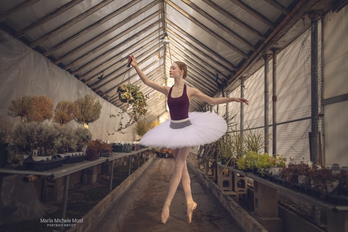 Dancer poses in a standing position in a greenhouse, captured by a Detroit-based photographer during a dance photoshoot.