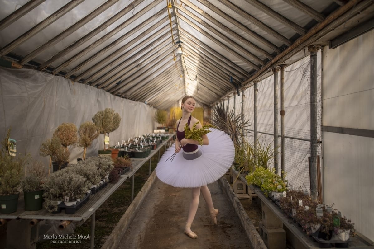 Dancer poses in a standing position in a greenhouse, captured by a Detroit-based photographer during a dance photoshoot.