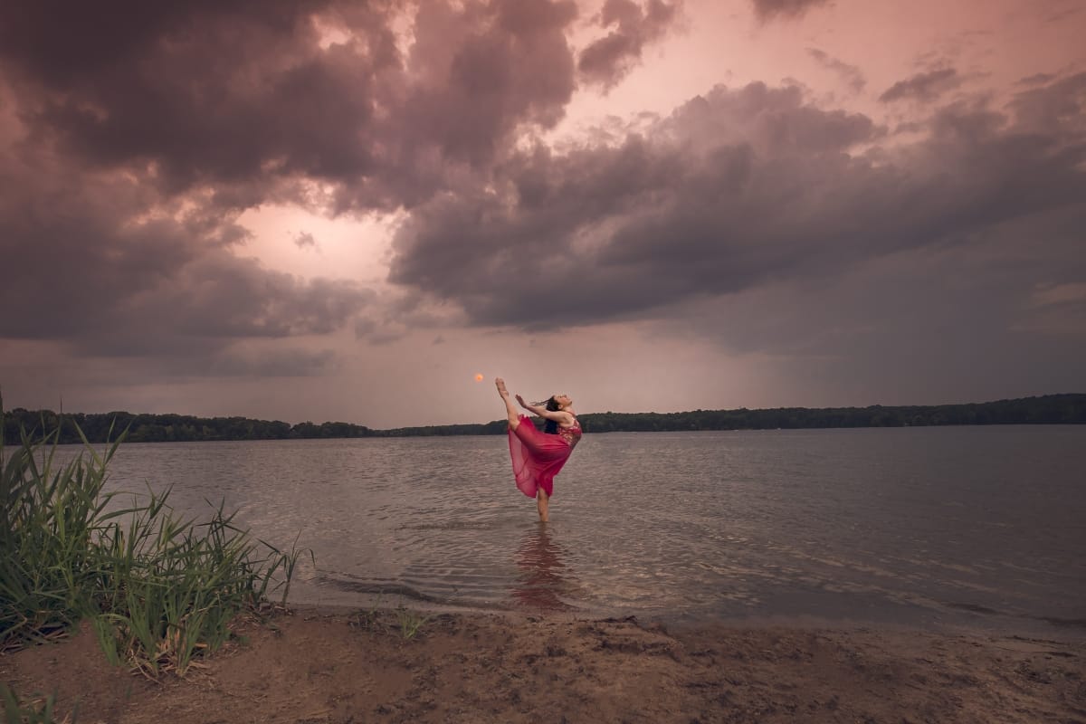 A Detroit dancer captures the essence of grace in a stunning leap during a dance photoshoot on a Michigan beach at sunset.
