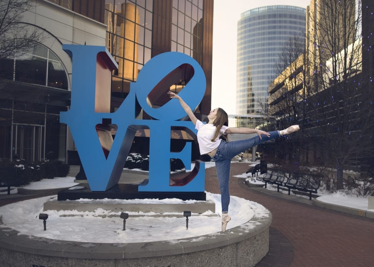 A dancer's arabesque is beautifully captured alongside a large sign spelling "LOVE", captured by a skilled portrait photographer from Detroit.