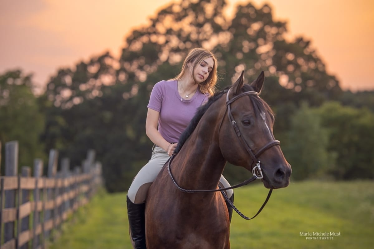 In the enchanting light of a sunset, a Detroit equine photographer captures a young woman calmly riding her horse towards the camera.