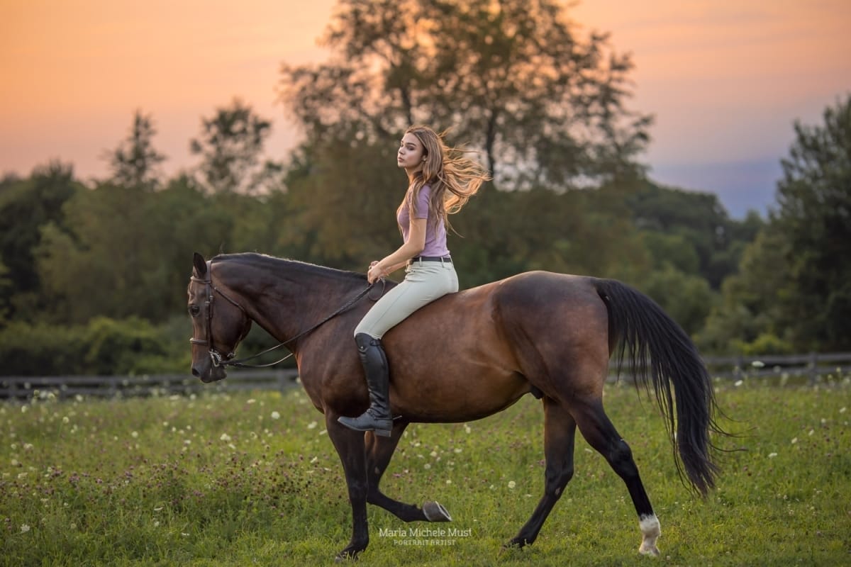 In the enchanting light of a sunset, a Detroit equine photographer captures a young horse and rider in profile of the camera.