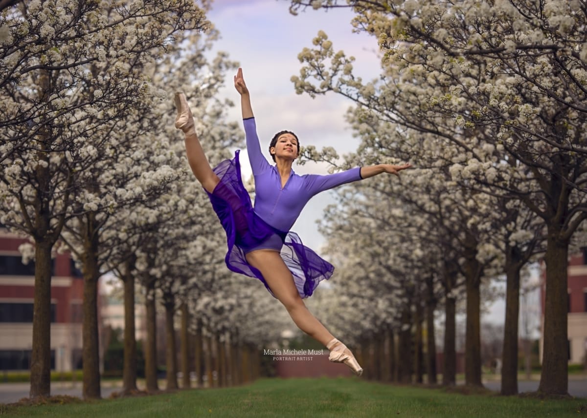 Impeccable technique showcased in a stunning portrait of a dancer in mid-air, taken by a talented Detroit photographer among a grove of evenly spaced cherry trees.