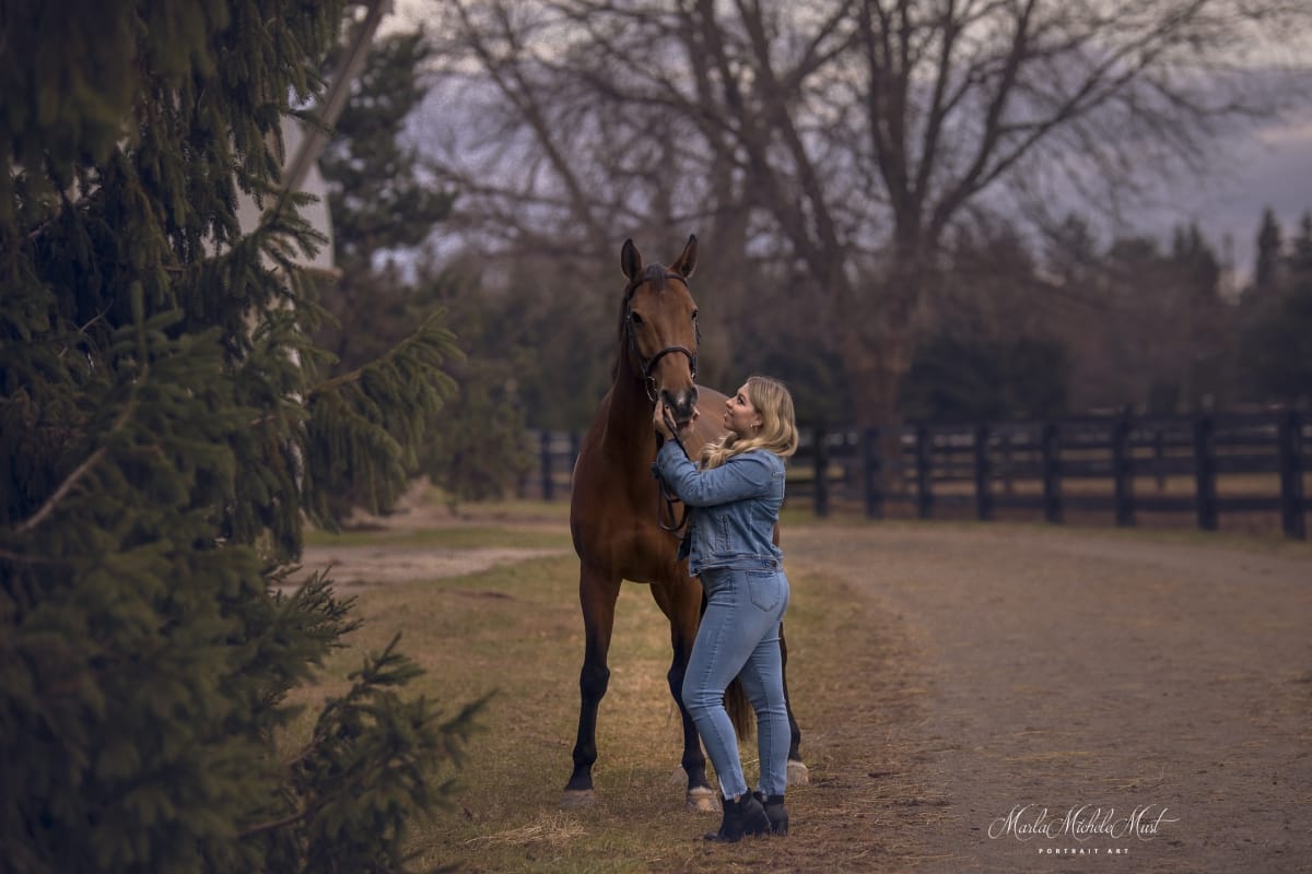 Dark autumnal photograph captured by a Detroit equine photographer, highlighting the bond between a horse and its owner against the backdrop of a fence.