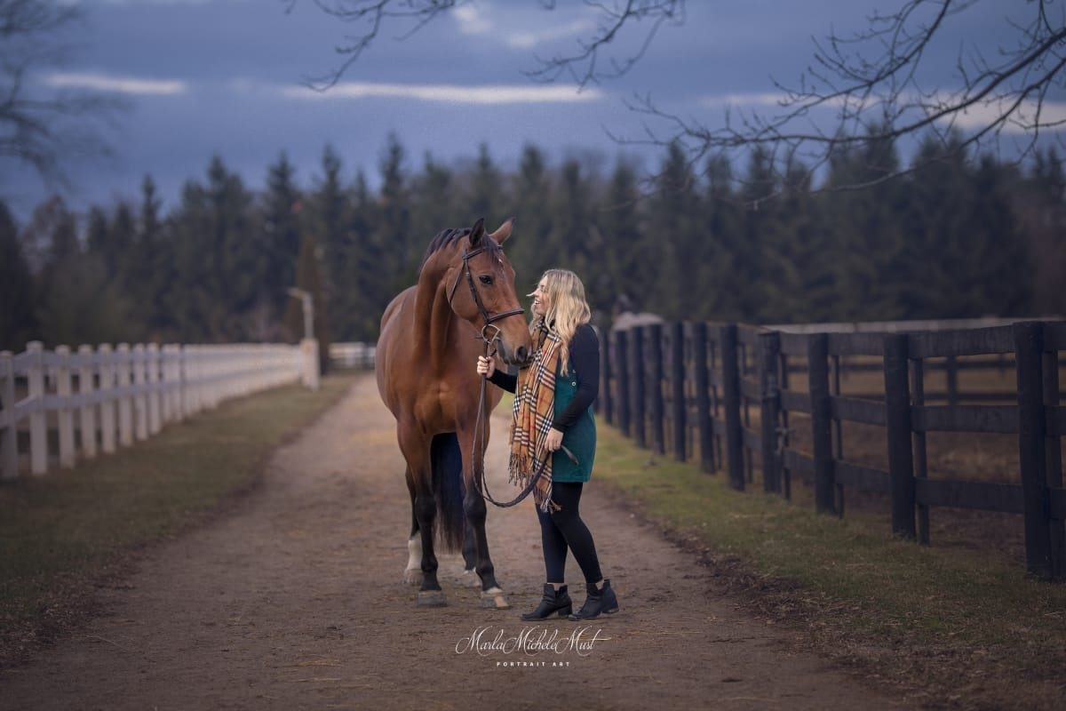 Dark and gentle autumnal moment captured by a Detroit equine photographer, highlighting the bond between a horse and its owner against the backdrop of a trail and fence.