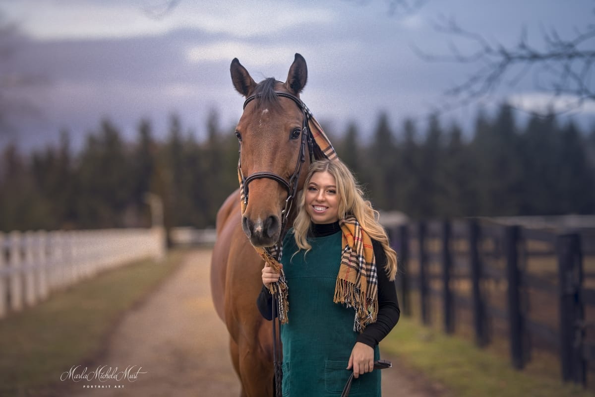 Enchanting photo taken by a Detroit equine photographer, showcasing the heartfelt connection between a horse and its smiling owner near a fence