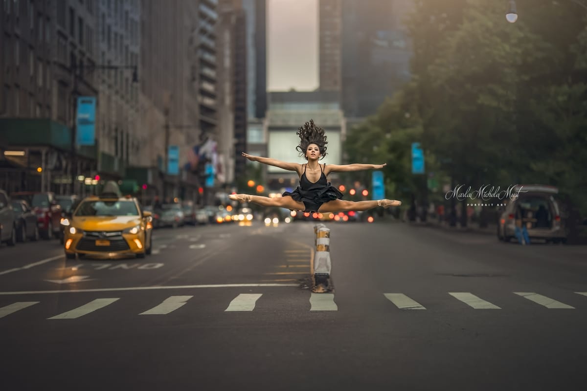 A dancer soars through the air in a splits pose before a busy city street , beautifully captured by a Detroit portrait photographer.