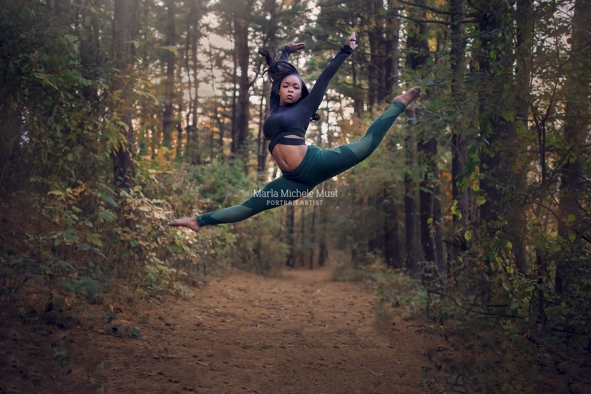 Dancer leaps with grace and precision, beautifully captured by a talented Detroit photographer during a dance photoshoot in a Michigan forest.
