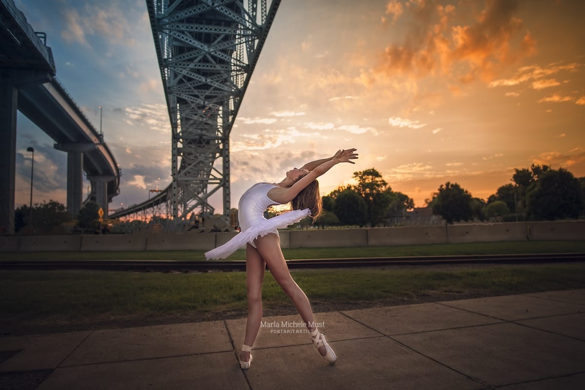 Dancer's lyrical pose shines in this captivating image from a dancer photoshoot with a talented Detroit photographer under a Michigan metro-area bridge at sunset.