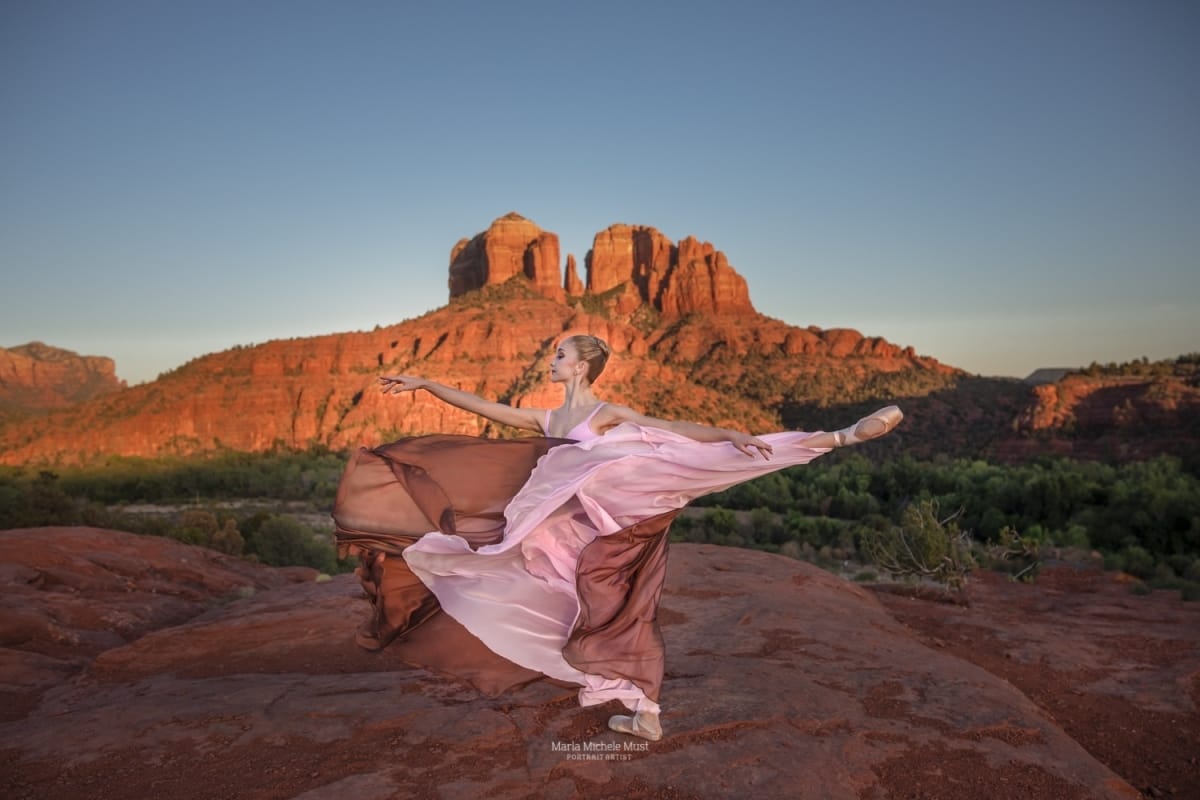 Dancer's lyrical pose shines in this captivating image from a dancer photoshoot with a talented Detroit photographer in a desert landscape, a rocky formation behind her.