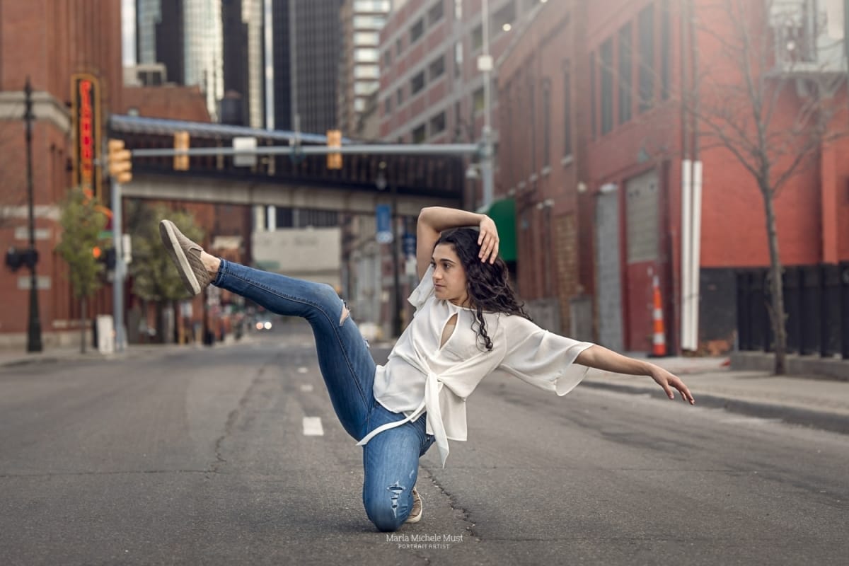 Dancer's effortless pose with one leg in the air shines in this captivating photo from a Detroit dancer photoshoot on a Detroit street..