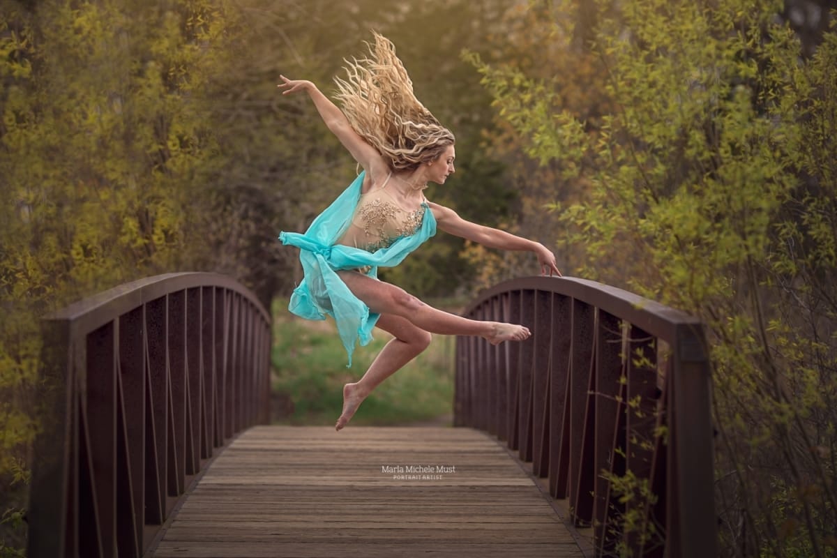 Dancer leaps with grace and precision in profile, beautifully captured by a talented Detroit photographer during a dance photoshoot on a bridge in a Michigan metro area bridge.