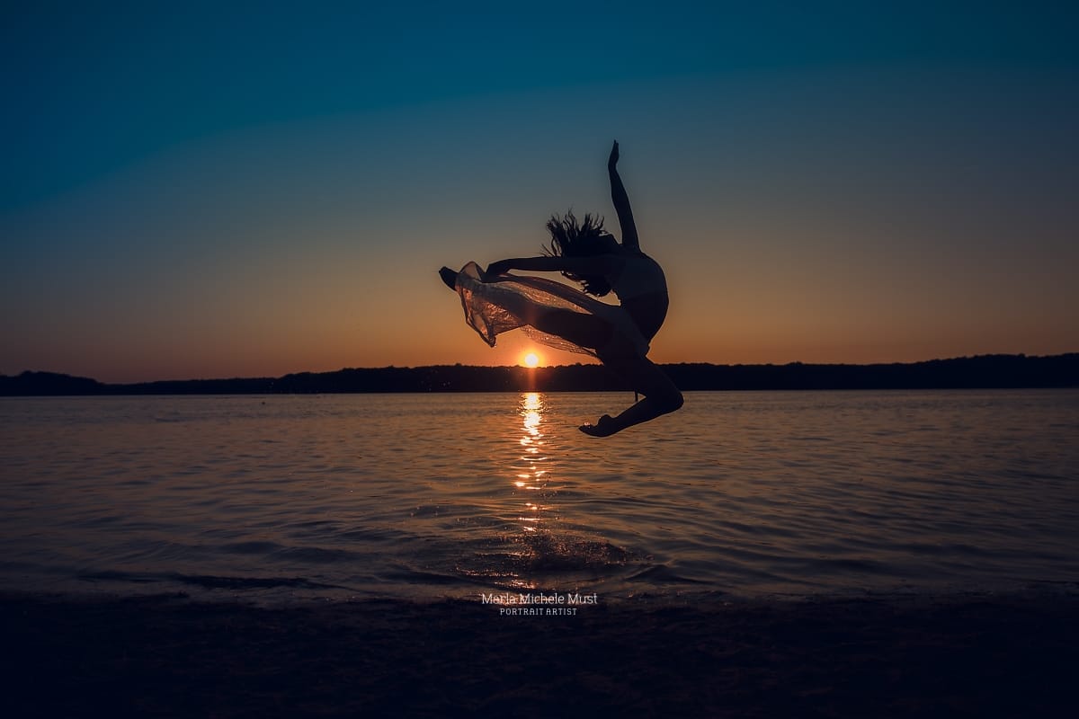 Breathtaking leap against a setting sun and ocean landscape, photographed during a dynamic photoshoot with a Detroit-based photographer.