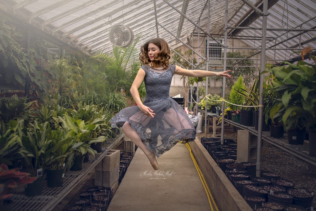 Dancer's lyrical pose shines in this captivating image from a dancer photoshoot with a talented Detroit photographer in a Michigan flower nursery during a dance photoshoot.