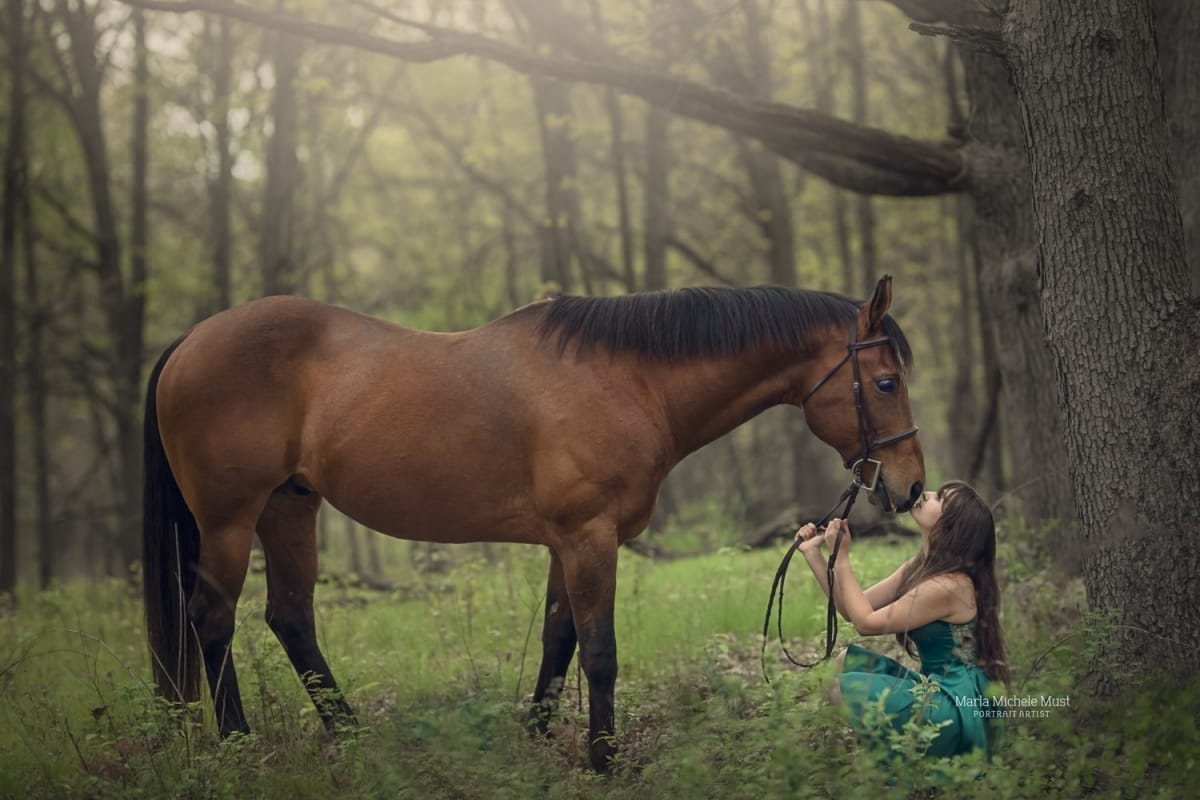 Peaceful Woodland photograph by a Detroit equine photographer, revealing the bond between a horse and its owner as she hold her horse's reins and nose gently above her.