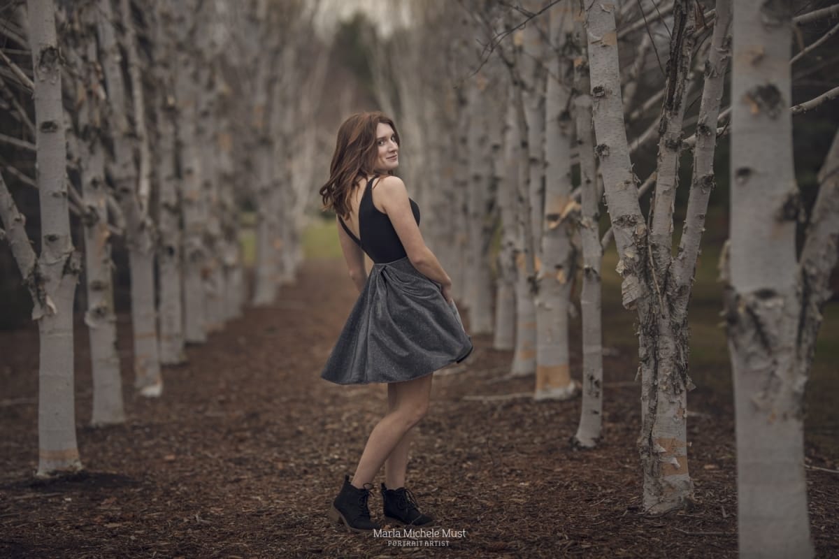 Senior picture taken of a girl twirling in her dress in a Michigan birch tree grove