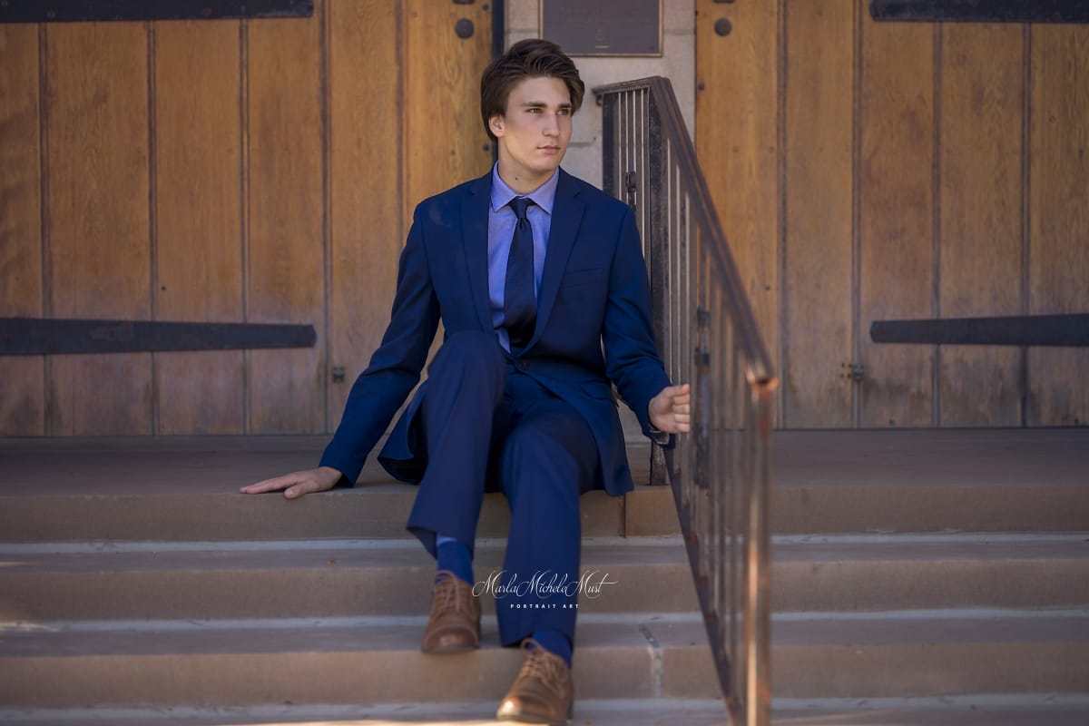Detroit-area High school senior photo of a young man in formal wear sitting on the steps of a corporate building