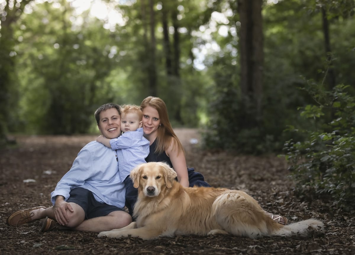 A couple sit with their baby and golden retriever for a local family photoshoot near Detroit.