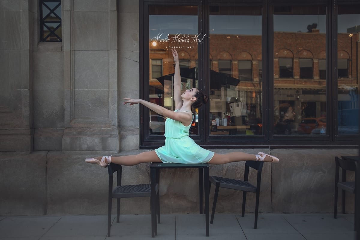 Posed on a Detroit sidewalk, a dancer does the splits between two chairs, her arms gracefully extended to the sky.