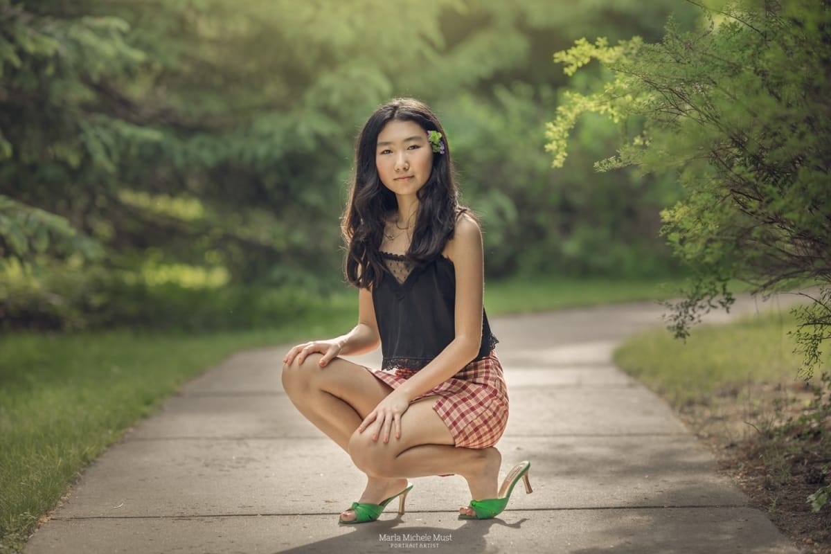 Detroit-area High school senior photographer captures the portrait of a girl kneeling down in a Detroit park