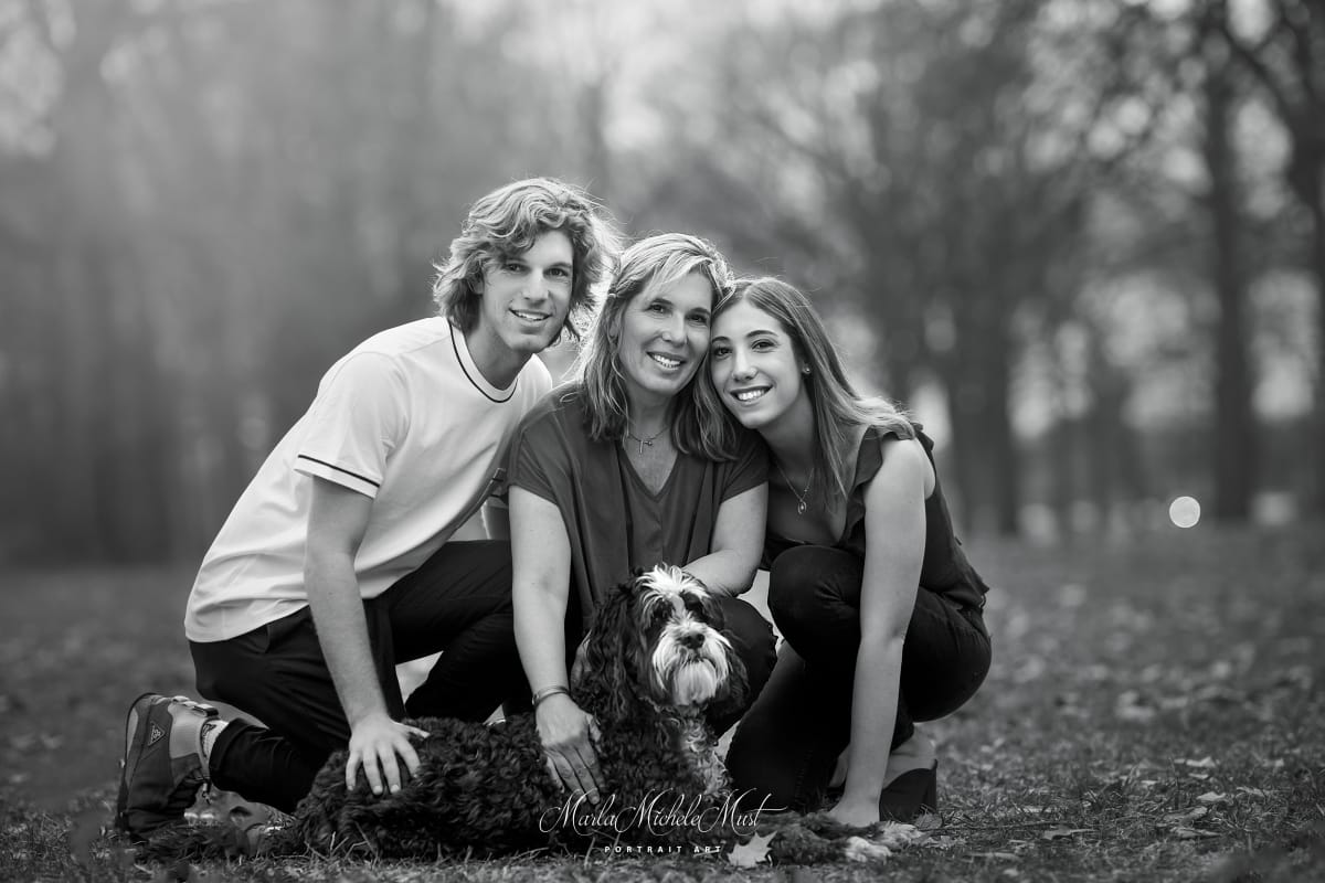A black and white photo of a woman, her two children and their dog pose for a family photographer in Grand Rapids.