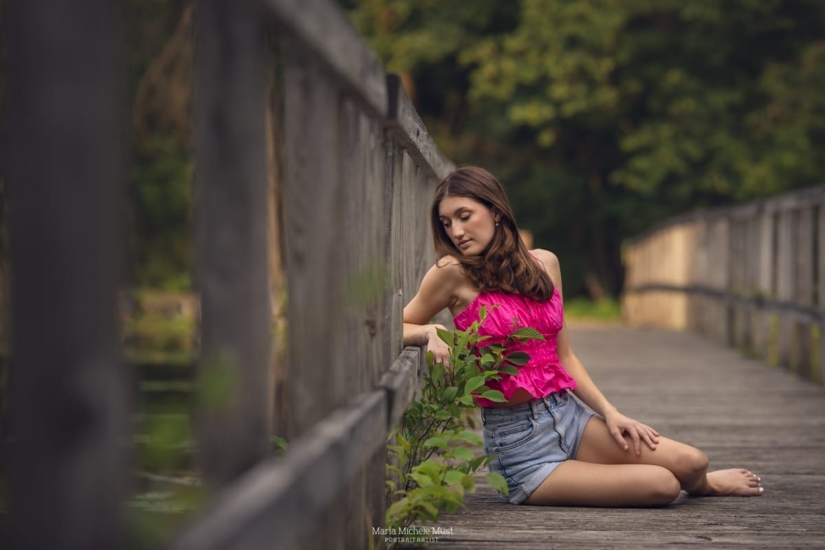 Girl poses while sitting on a bridge in Detroit for her senior photos
