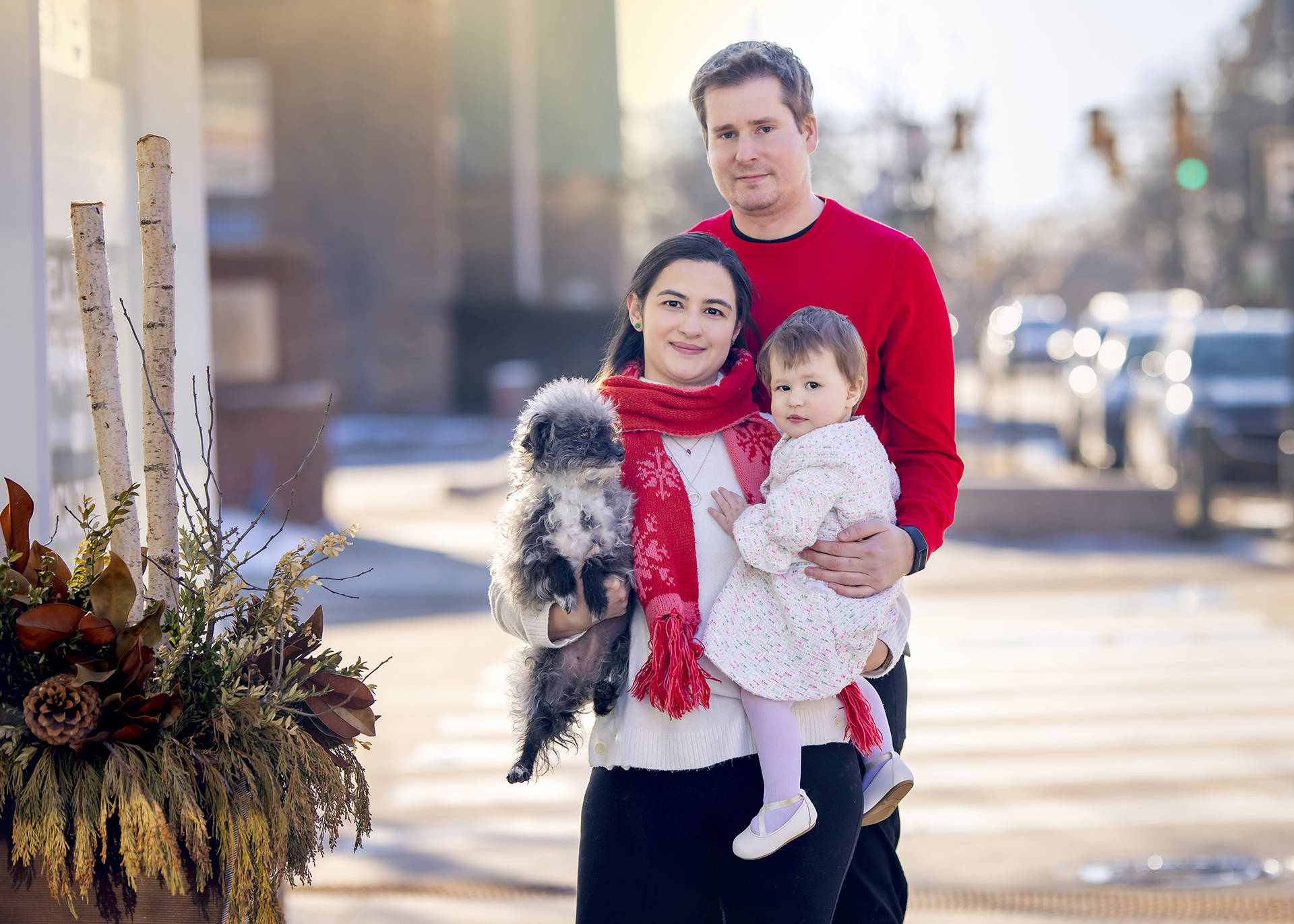 A Detroit holiday family photoshoot of a couple and their young baby as they each wear matching white and red outfits while in the city.