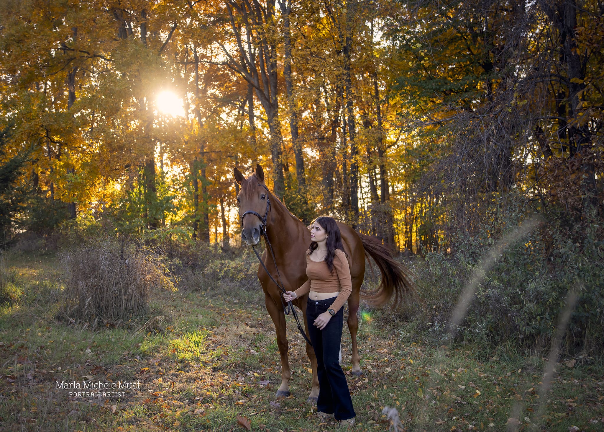 A Detroit equine photographer's portrait: Horse owner gently grasping the horse's nose against a summer sunset and woodland forest..
