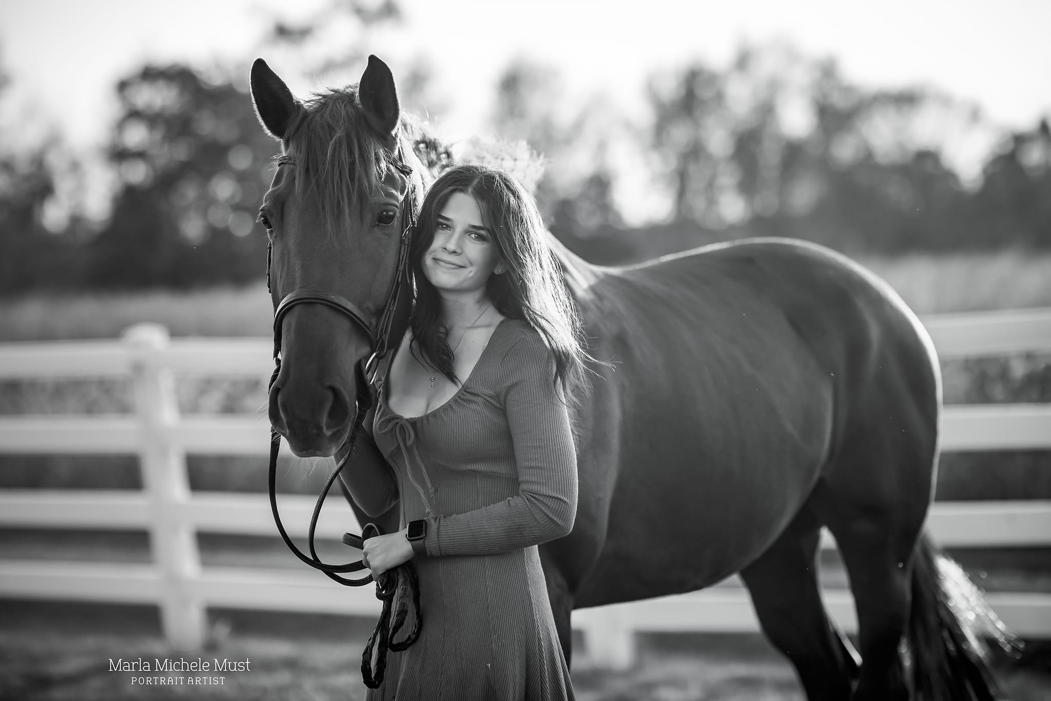 A memorable black and white photograph by a Detroit equine photographer, illustrating the heartwarming bond between a horse and rider standing proudly next to each other as she hold the reigns and smiles.