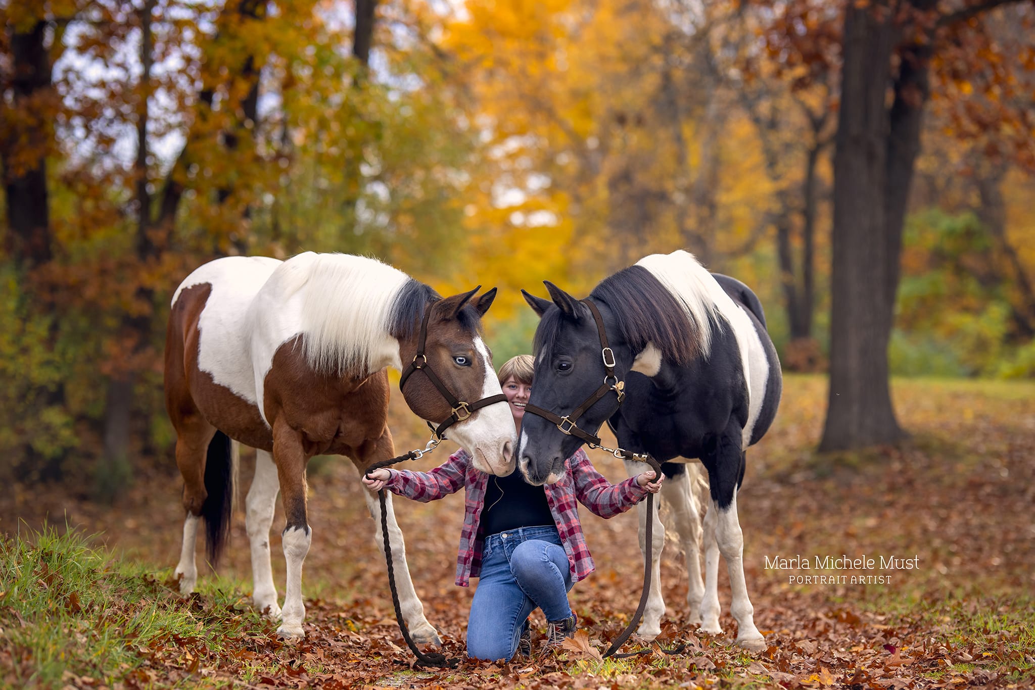 Detroit horse photographer's shot: Horse owner knelt down while holding the reins of two horses, guiding them along a trail.