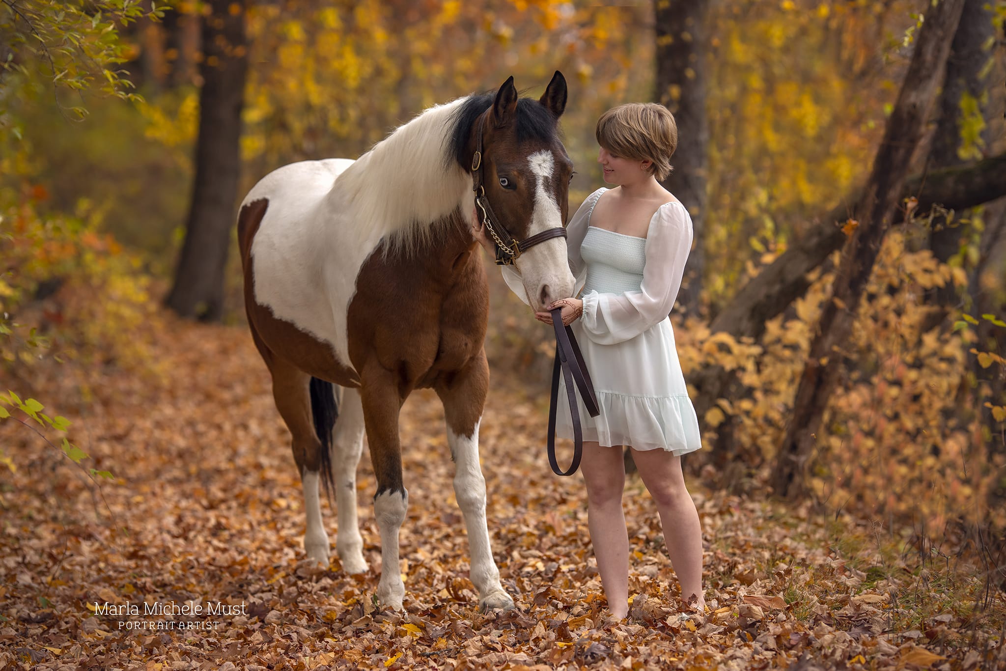 A serene photograph captured by a Detroit equine photographer unfolds as a woman stands among the fallen leaves, accompanied by a graceful horse.