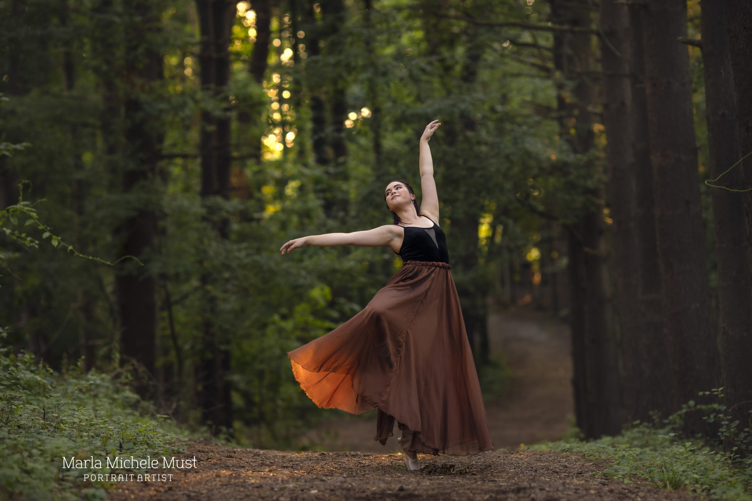 Dancer poses gracefully in a Detroit forest during a dance photoshoot, taken by a Michigan dance photographer.