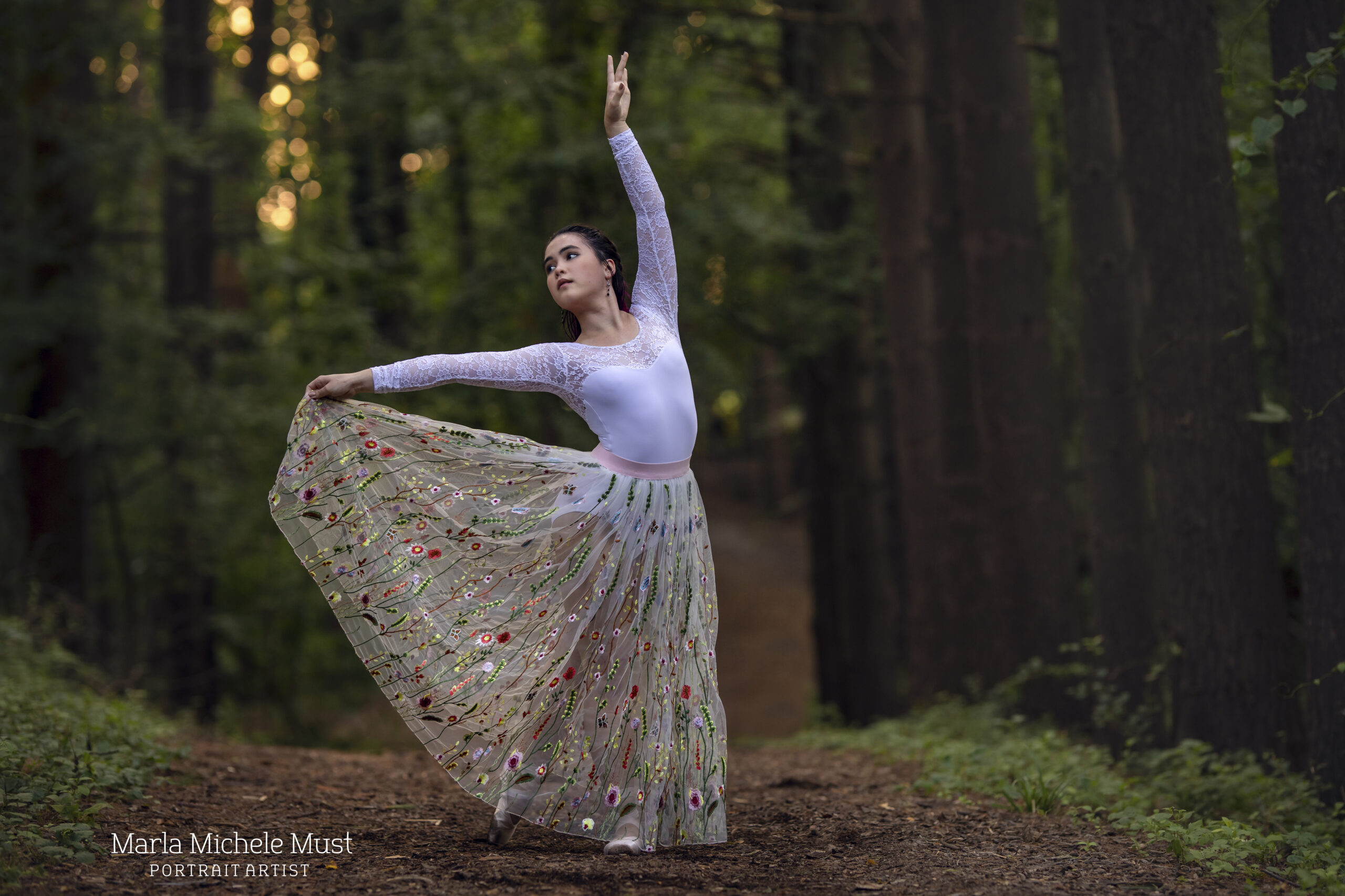 Dancer holds her skirt and looks off camera while reaching one arm in the air during a dance photoshoot, taken by a Michigan dance photographer.