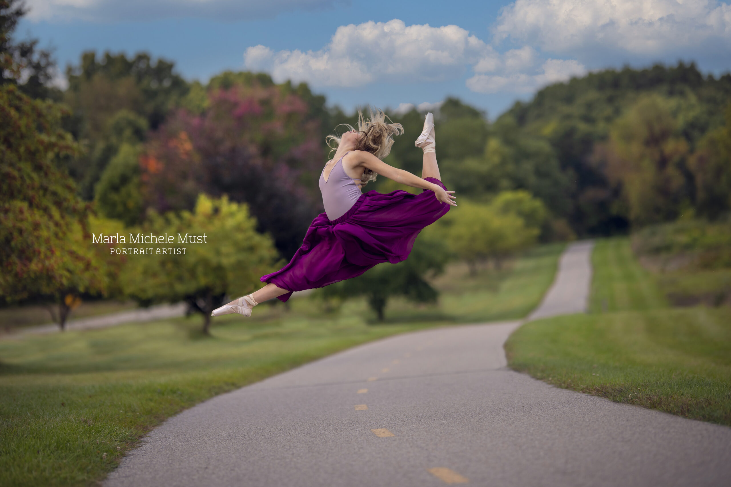 Woman jumps in the air on a park pathway during a dance photoshoot, taken by a Michigan dance photographer.